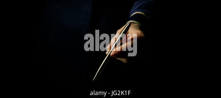 Black Mania. female hand isolated on black giving a pen Stock Photo