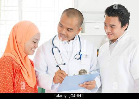 Medical team discussing treatment options with patients. Southeast Asian Muslim people. Stock Photo