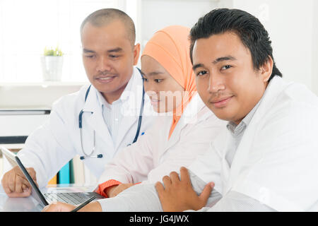 Medical team using a laptop in a bright office. Southeast Asian Muslim doctors and nurses. Stock Photo