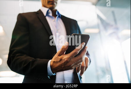 Close up of male hands reading ext message on smart phone. Businessman man hand using mobile phone in office. Stock Photo
