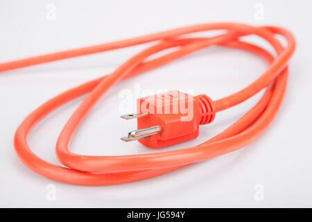 Bright orange extension cord on a white surface. Orange extension cable isolated on white background. Stock Photo