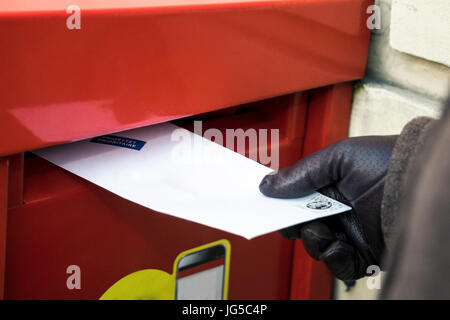 Sending a letter. Putting it to the red post box Stock Photo