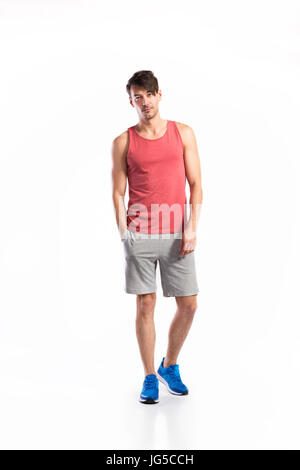 Handsome hipster fitness man in red tank top shirt and gray shorts. Studio shot on white background. Stock Photo