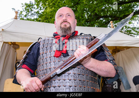 A large man holds a large, dangerous medieval sharp bladed axe. Stock Photo