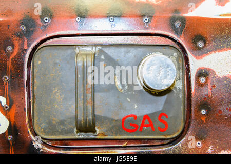 Top of a petrol can stuck on the fuel filler of an old, rusty car with rivets and 'GAS' written on it. Stock Photo