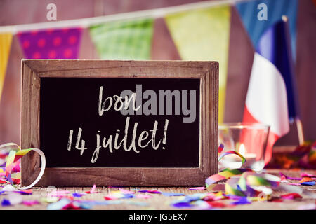 chalkboard with the text bon 14 juillet, happy 14 July, the National Day of France, written in French and a flag of France, on a wooden surface sprink Stock Photo
