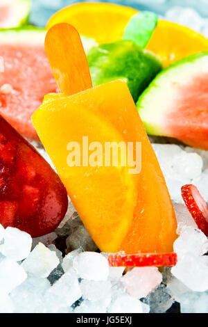 some different homemade natural ice pops made with natural fruit juices and pieces of fruit, on ice Stock Photo