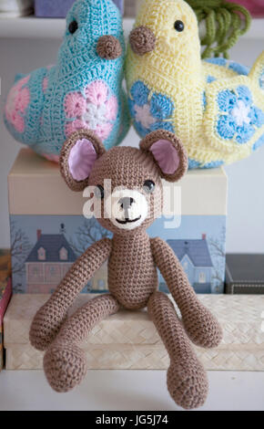 Crocheted Teddy Bear and Birds sitting on boxes in nursery Stock Photo