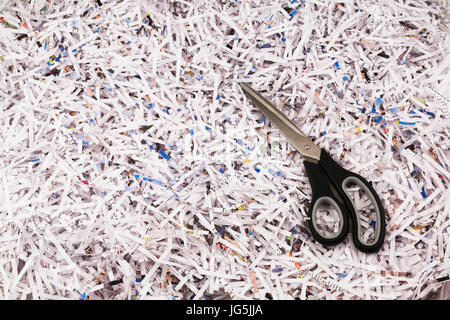 Black scissors on top of strips of shredded paper Stock Photo