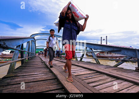 Workers unloading cargo from boats onto awaiting lorries at a dock in Yangon, Myanmar Stock Photo