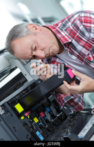 male tech trying to repair the office printer Stock Photo