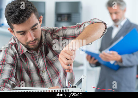 technician installing digital thermostat using screwdriver Stock Photo