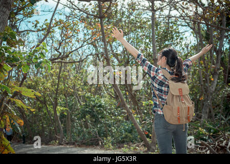 happy pretty woman traveler standing in forest path and opening arms enjoying nature when she travel to hiking at national park. Stock Photo