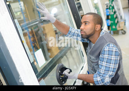 master with a screwdriver sets fittings on the window Stock Photo