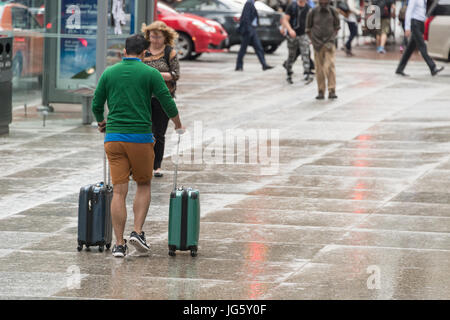 Toronto, Canada - 26 June 2017: Man with spinner luggage walking in Toronto Downtown on a rainy day Stock Photo