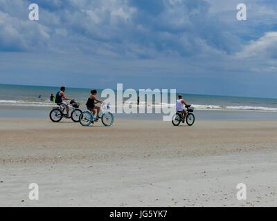 People riding bikes on Florida beach and playing in the Atlantic Ocean. St. Augustine Beach, Florida, USA. Stock Photo