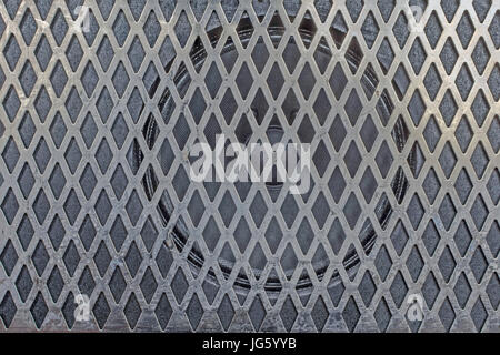 Speaker mounted on a black panel behind a sliver metal grid Stock Photo