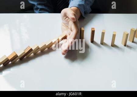 businessman hand stop dominoes continuous toppled or risk with copyspace Stock Photo