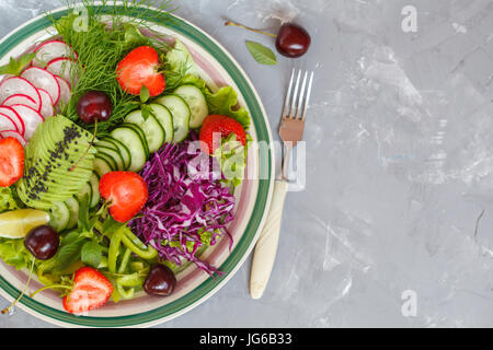 Bright summer salad of vegetables and berries. Love for a healthy vegan food concept. Stock Photo