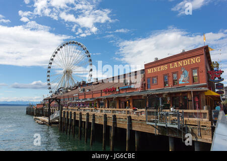 Miners Landing (pier 57) with the Seattle Great Wheel (ferris wheel) and the Olympic Mountains in the background - Seattle, Washington Stock Photo