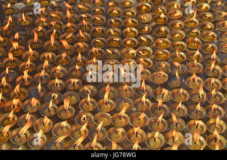 Group of burning oil lighting up candles lamps in buddhist temple - Great stupa Bodnath in Kathmandu, Nepal. Stock Photo