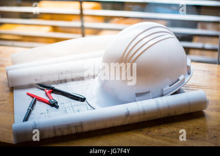 construction concept image helmet rolled blueprints on wooden boards in retro style. Stock Photo