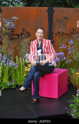 Charlie Bloom, garden designer, sitting in her Colour Box Garden, one of the beautiful and elegant show gardens on display at the 2017 RHS Hampton Court Flower Show which opened today in the grounds of Hampton Court Palace, London, United Kingdom.  The RHS Hampton Court Palace Flower Show is the world’s largest flower show boasting an eclectic mix of gardens, displays and shopping opportunities spanning over 34 acres either side of the dramatic long water with the stunning façade of the historical palace in the background. Around 130,000 people attend the show each year.  The show was first he Stock Photo