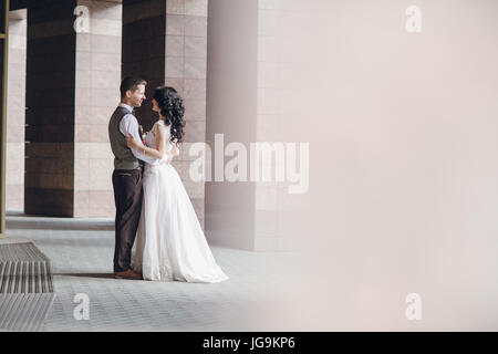 bride and groom stand near tall columns Stock Photo