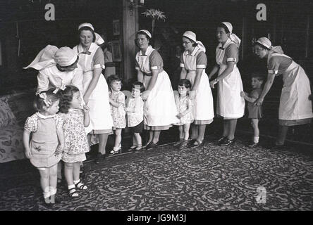 1940, England, wartime, Stanstead Hall, country home of Lady Butler (Sydney Courtauld) wife of Rab Butler, Conservative politician, picture shows domestic staff indoors lining up with the child evacuees from London. Stock Photo