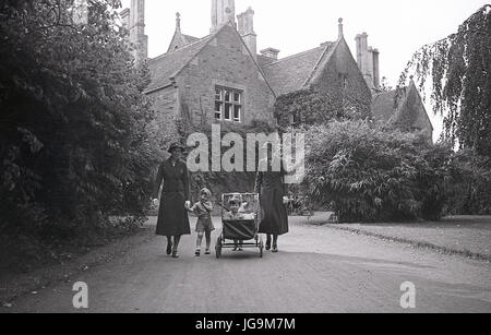 1940s, England, wartime, picture shows the exterior of Stanstead Hall, home of Lady Butler (Sydney Courtauld) wife of Rab Butler, Conservative politiican and minister, two nurses walk a pram in the driveway with evacuated children from Hampstead garden Suburbs, London. Stock Photo