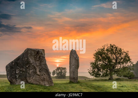 The clouds part as dawn breaks over the ancient Sarsen Stones at Avebury in Wiltshire on the day before the Summer Solstice. Stock Photo