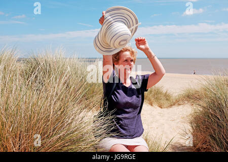 Southwold Suffolk UK June 2017 - Middle aged woman with sun hat on Southwold beach and sand dunes Stock Photo