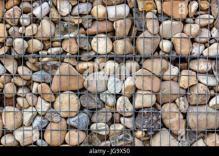 metallic basket net filled by natural stones as a fence Stock Photo
