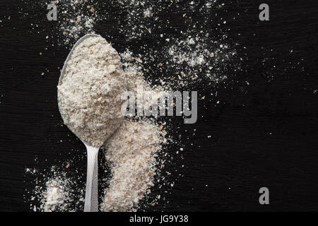 Spoonful of flour on black wooden background Stock Photo