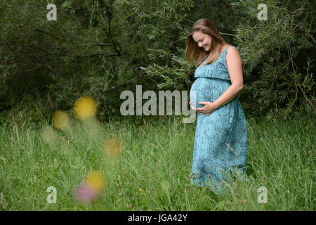 Pregnant young woman standing in a park Stock Photo