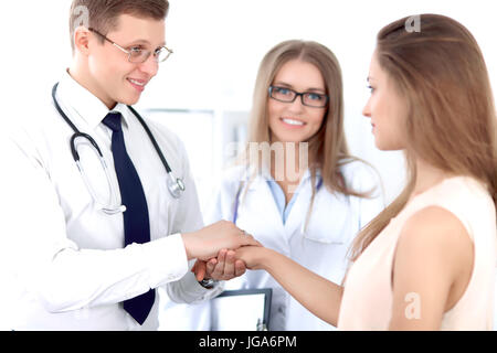 Friendly male doctor and female patient shaking hands.  Stock Photo