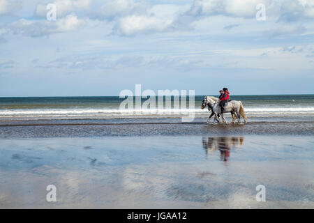 Three women riding horses on Satburn beach and sea in north east England,UK Stock Photo