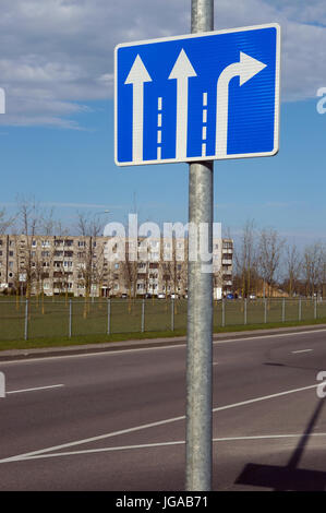 A blue light reflecting  road sign with white arrows is located on the central city highway. Two lanes of traffic - just straight, one-way - just to t Stock Photo