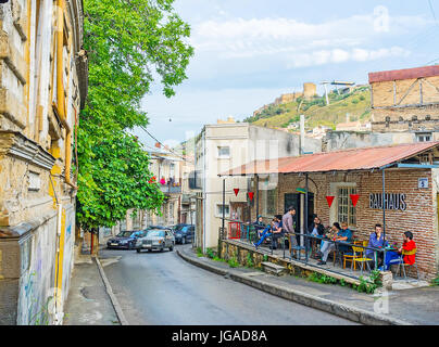 TBILISI, GEORGIA - JUNE 5, 2016: The small street bar was created in the old ruined building with preserved facade wall, on June 5 in Tbilisi. Stock Photo