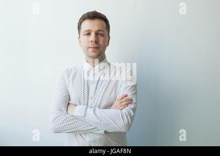 Smiling young man standing with arms crossed Stock Photo