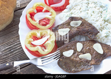 Fried pork liver in plate with salad and fork Stock Photo