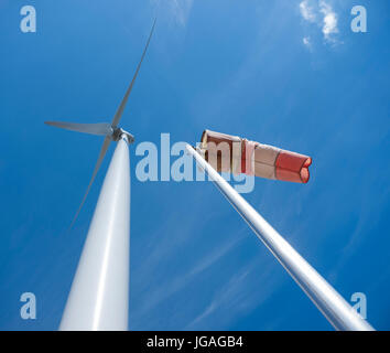 red and white windbag and wind turbine against background of blue sky Stock Photo