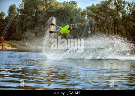 Wakeboarder young athlete, he jumped over the water creating a splash. Stock Photo