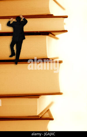 pile of books with a businessman climbing it, concept for success through education Stock Photo
