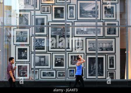 People walk past a window full of picture frames and artwork Stock Photo