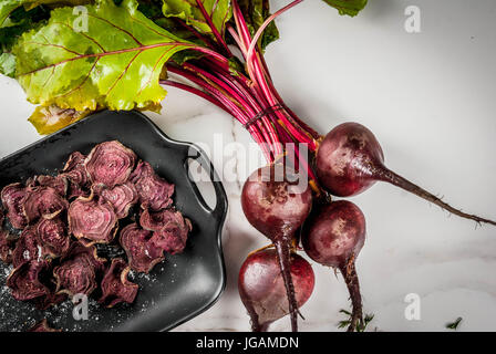 Organic diet food. The vegan diet. Dried vegetables. Homemade chips from beets. On a white marble table, with fresh beetroot Top view copy space. Stock Photo