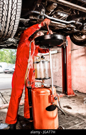 Mechanic hooking up equipment to the undercarriage of a car elevated on a hoist during repairs and maintenance in a garage workshop Stock Photo