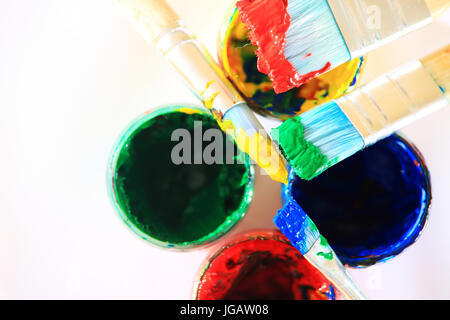 Colorful art background. Brushes with paint on paint boxes close-up. Stock Photo