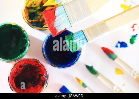 Bright art background. Brushes in colorful paint from above close-up. Stock Photo