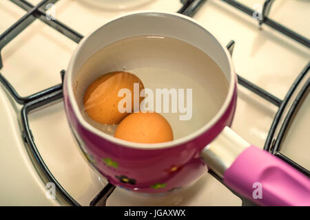 Boiling two eggs in water in stainless steel pan Stock Photo